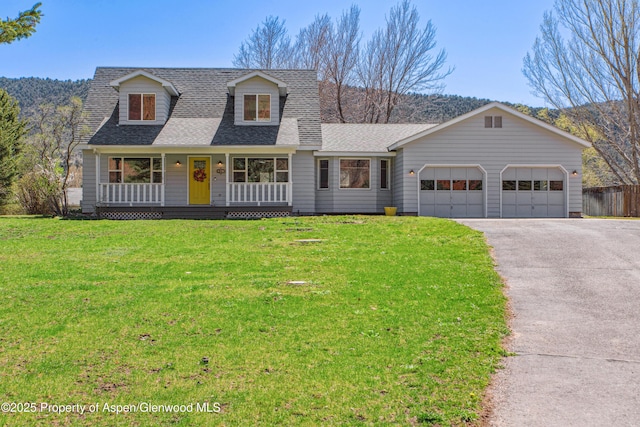 cape cod-style house featuring aphalt driveway, an attached garage, a porch, roof with shingles, and a front yard