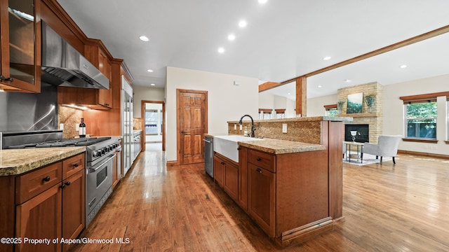 225 Juniper Ct, Basalt, CO 81621 - kitchen with appliances with stainless steel finishes, exhaust hood, decorative backsplash, light wood-style flooring, and glass insert cabinets