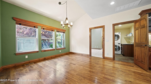 225 Juniper Ct, Basalt, CO 81621 - unfurnished room with a chandelier, estacked washer and dryer, wood finished floors, vaulted ceiling, and recessed lighting
