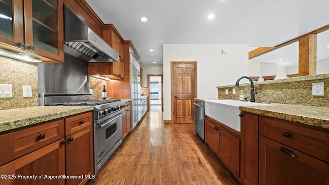225 Juniper Ct, Basalt, CO 81621 - kitchen featuring appliances with stainless steel finishes, range hood, light wood-type flooring, decorative backsplash, and light stone countertops