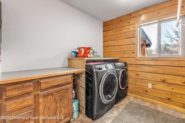 laundry room featuring light tile patterned flooring, washing machine and dryer, and wooden walls