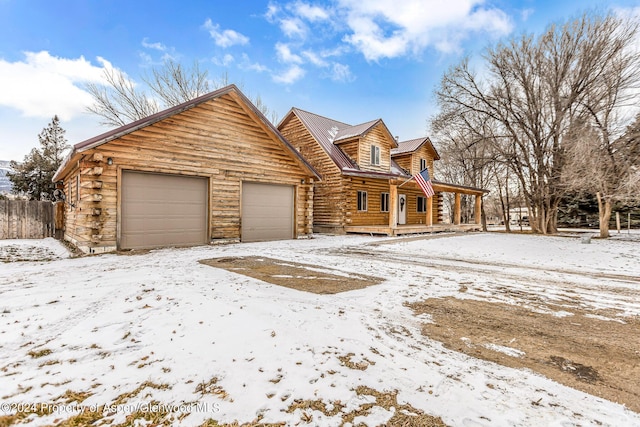 log home featuring covered porch and a garage