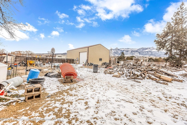 snowy yard with a mountain view, an outbuilding, and a garage