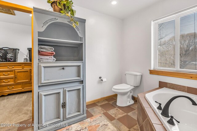 bathroom with a relaxing tiled tub and toilet