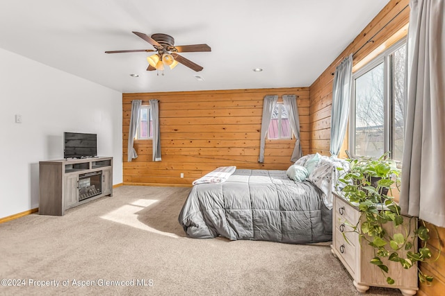 carpeted bedroom featuring ceiling fan and wood walls