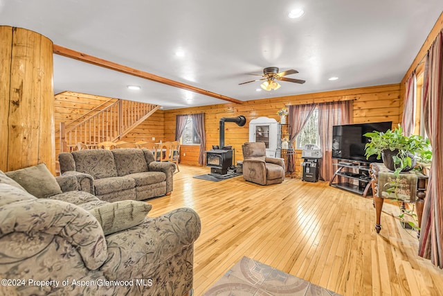 living room with a wood stove, wood walls, and light hardwood / wood-style floors