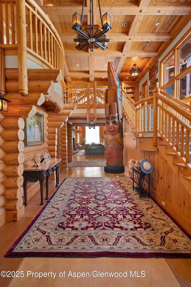 interior space featuring rustic walls, an inviting chandelier, beamed ceiling, stairs, and wood ceiling