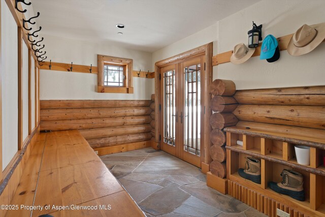 doorway featuring stone floors, log walls, and french doors