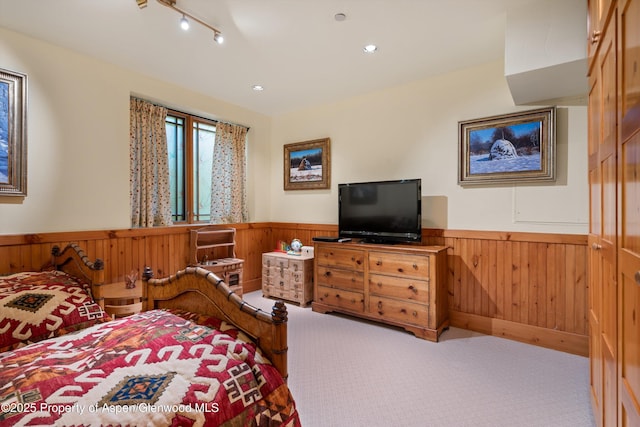 carpeted bedroom featuring a wainscoted wall, wooden walls, and recessed lighting