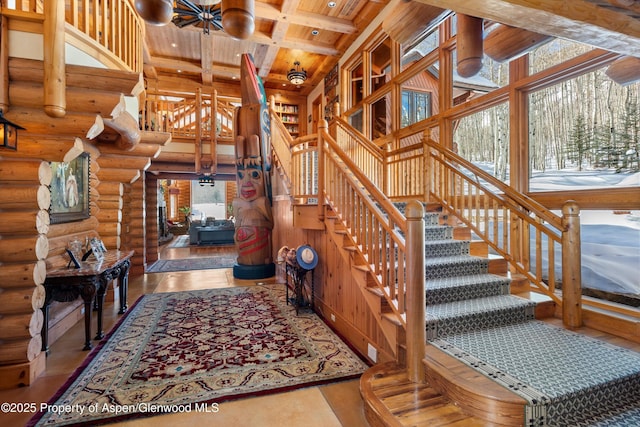 stairway featuring an inviting chandelier, beamed ceiling, log walls, a high ceiling, and wooden ceiling