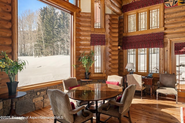 dining space with rustic walls, a high ceiling, and hardwood / wood-style flooring