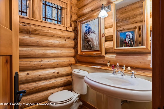 bathroom with rustic walls, toilet, and a sink