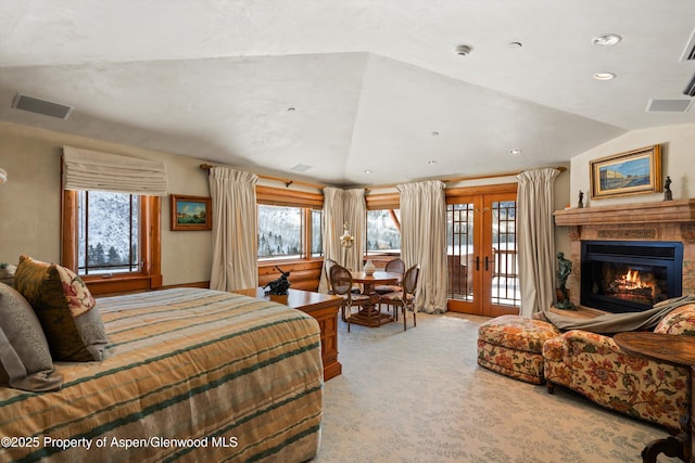 carpeted bedroom featuring french doors, vaulted ceiling, a glass covered fireplace, visible vents, and access to outside