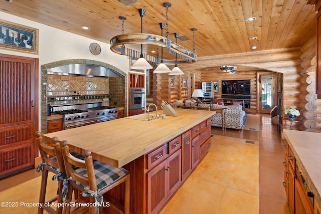kitchen with butcher block counters, log walls, open floor plan, and appliances with stainless steel finishes