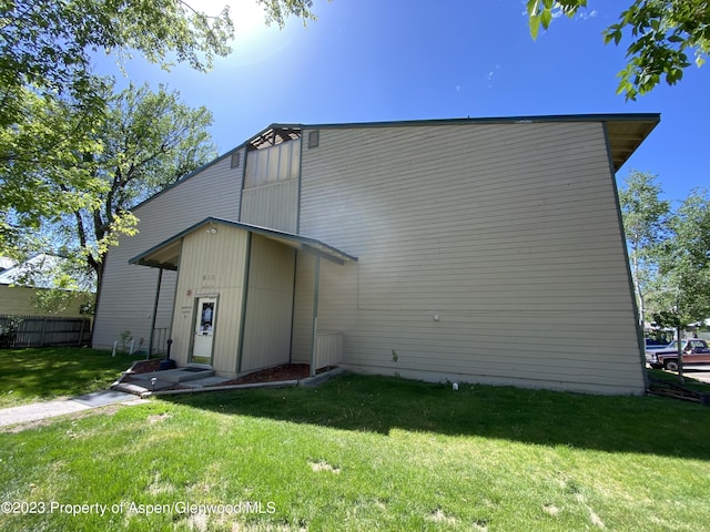 rear view of house with a lawn and fence