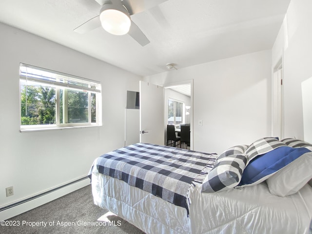 carpeted bedroom featuring a baseboard heating unit and a ceiling fan