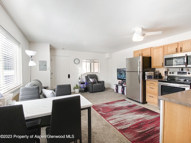 kitchen featuring light brown cabinets, electric panel, stainless steel appliances, light colored carpet, and open floor plan