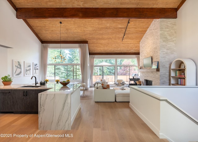 65 Harleston Grn Unit 51, Snowmass Village, CO 81615 - kitchen featuring a wooden ceiling with exposed beams, high vaulted ceiling, a fireplace, light countertops, and light wood-style flooring