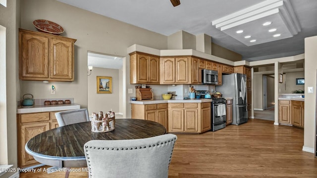 kitchen with light countertops, appliances with stainless steel finishes, brown cabinetry, and wood finished floors