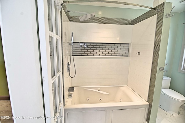 bathroom with tiled shower / bath combo, washer / clothes dryer, and toilet