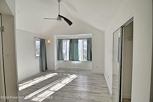 unfurnished bedroom with ceiling fan, a closet, lofted ceiling, and light hardwood / wood-style flooring