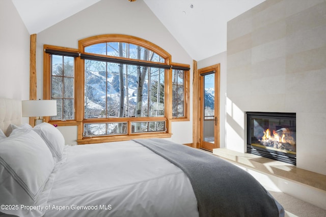 bedroom with a tiled fireplace and vaulted ceiling