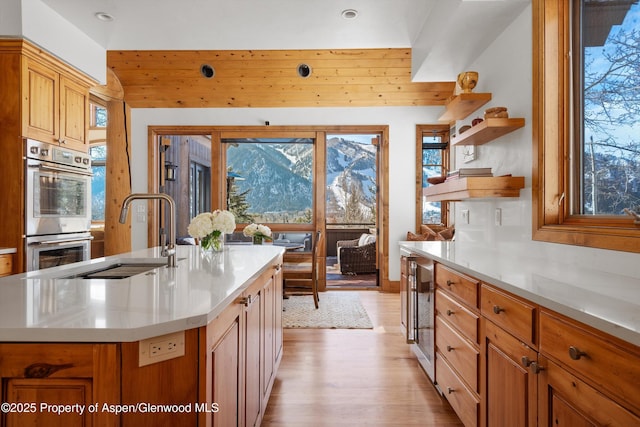 kitchen featuring a kitchen island with sink, sink, a wealth of natural light, and stainless steel double oven