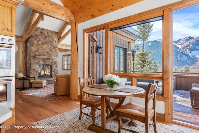 dining area featuring vaulted ceiling, a mountain view, a fireplace, and light hardwood / wood-style flooring