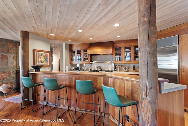 172 Deer Ridge Ln, Snowmass Village, CO 81615 - indoor wet bar featuring wall chimney range hood, recessed lighting, appliances with stainless steel finishes, wood-type flooring, and wooden ceiling