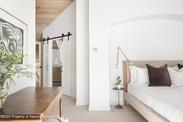 172 Deer Ridge Ln, Snowmass Village, CO 81615 - bedroom featuring a barn door, light colored carpet, lofted ceiling, baseboards, and ensuite bathroom