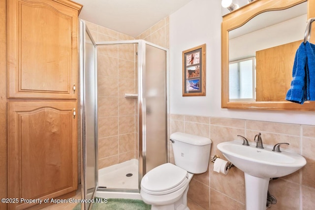 bathroom featuring tile walls, a stall shower, and toilet
