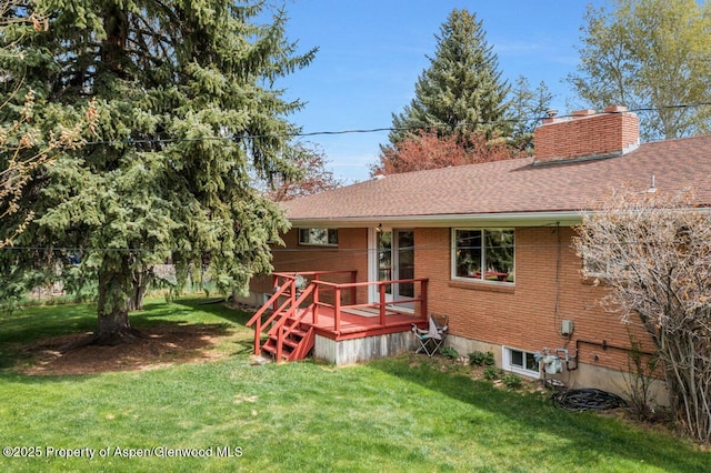 rear view of property with a lawn, a chimney, a deck, and brick siding