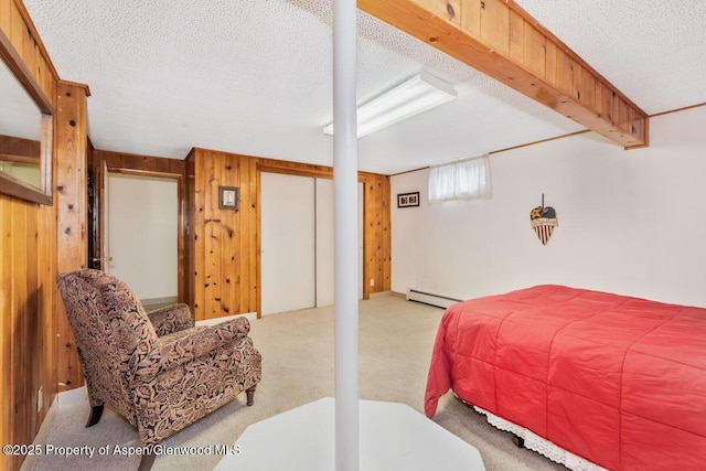 bedroom featuring carpet floors, wooden walls, a textured ceiling, and a baseboard heating unit