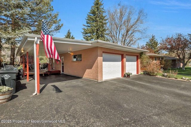 view of side of property with brick siding, driveway, a carport, and a garage