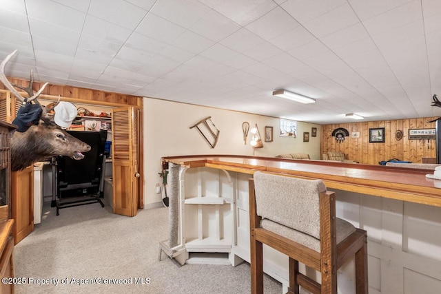 bar with light colored carpet, wood walls, and a bar