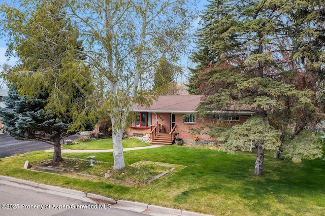view of front of home with brick siding, covered porch, and a front yard