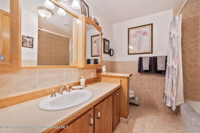 full bath with a tile shower, vanity, tile patterned floors, tile walls, and a baseboard radiator