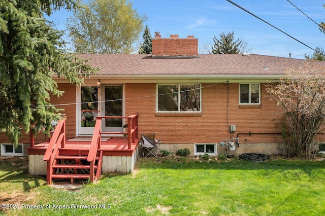 back of house featuring a lawn, brick siding, a chimney, and a deck