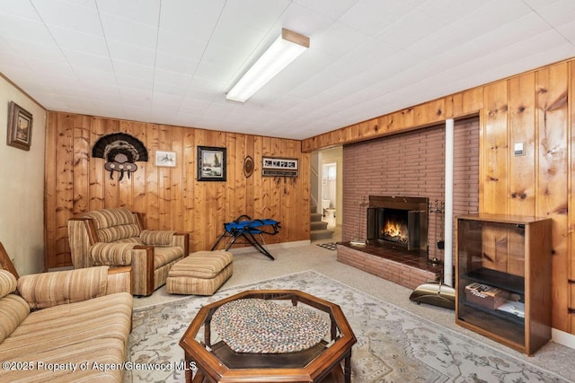 living room featuring baseboards, carpet, a brick fireplace, and wood walls