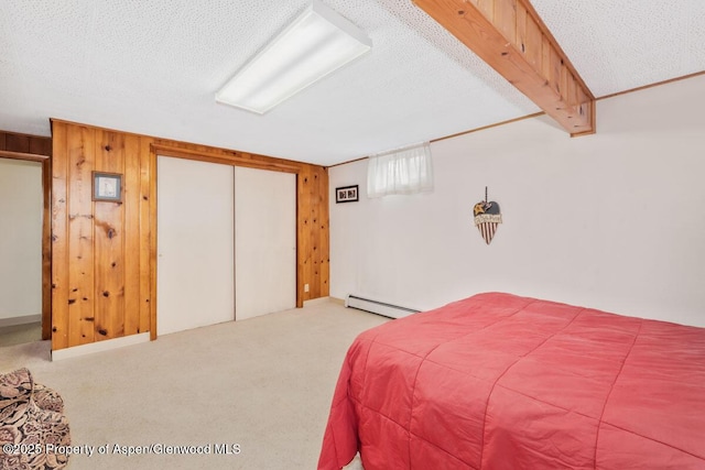 carpeted bedroom featuring a closet, a baseboard heating unit, wood walls, and a textured ceiling