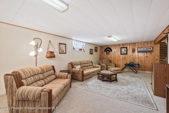 living area with wooden walls, baseboards, and light carpet