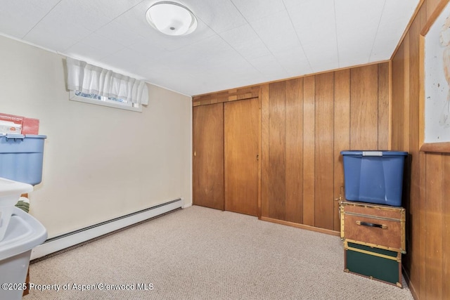 below grade area featuring wood walls, baseboard heating, and carpet