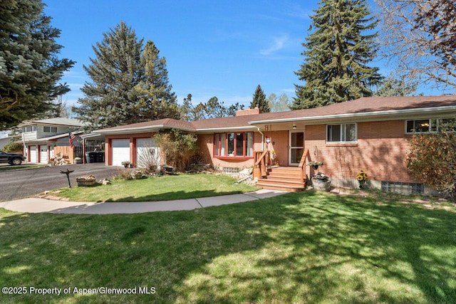 ranch-style home with a garage, brick siding, a front lawn, and aphalt driveway