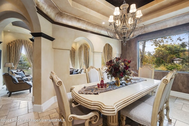 dining area featuring a tray ceiling, a healthy amount of sunlight, and a notable chandelier