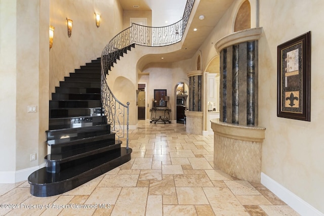 foyer with a towering ceiling and ornate columns