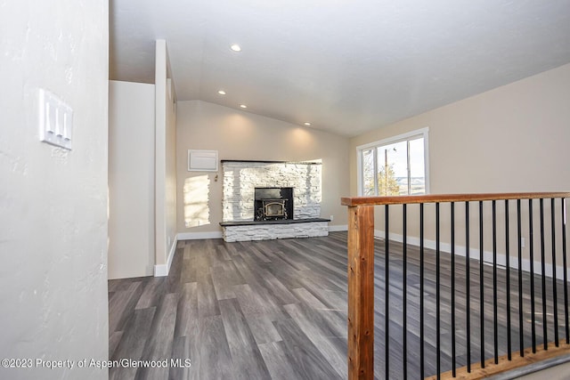 unfurnished living room with lofted ceiling, a wood stove, and hardwood / wood-style floors