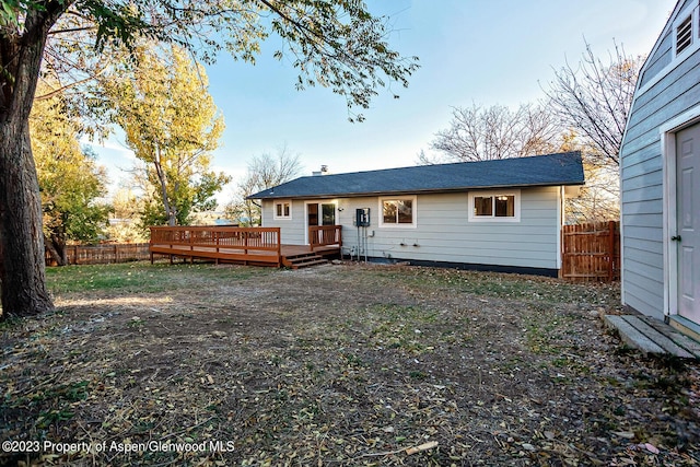 back of property with a wooden deck, a shed, and a lawn