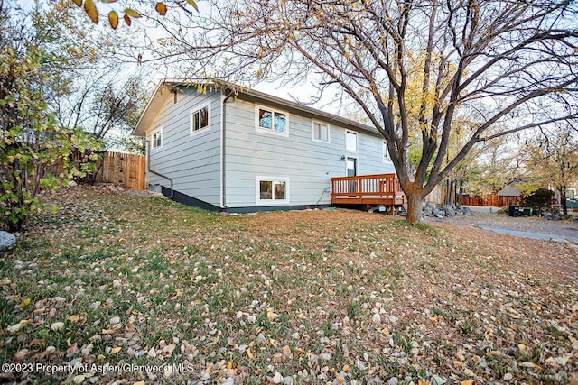 rear view of house featuring a wooden deck and a lawn
