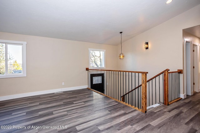 spare room with lofted ceiling and dark wood-type flooring