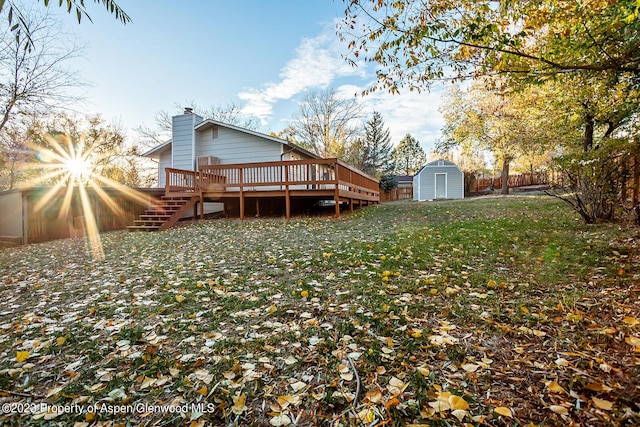 rear view of house featuring a wooden deck, a storage unit, and a lawn
